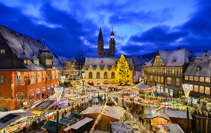 Winterlicher Weihnachtsmarkt mit festlich beleuchteten Buden und geschmücktem Baum.