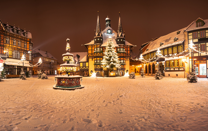 Verschneiter Marktplatz mit beleuchteten Fachwerkhäusern und Weihnachtsbaum.