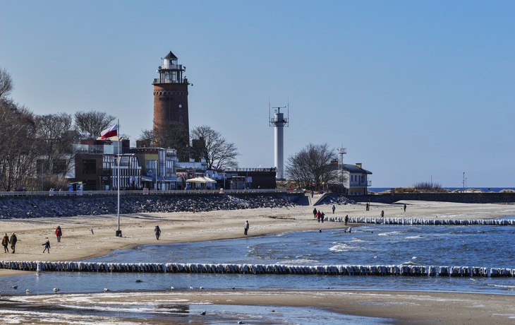 Kolobrzeg im Winter© Gehkah - stock.adobe.com Strand mit Leuchtturm im Hintergrund bei klarem Himmel.