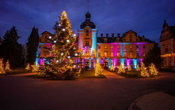 Beleuchtetes Schloss mit weihnachtlicher Dekoration und Lichtern in der Dunkelheit