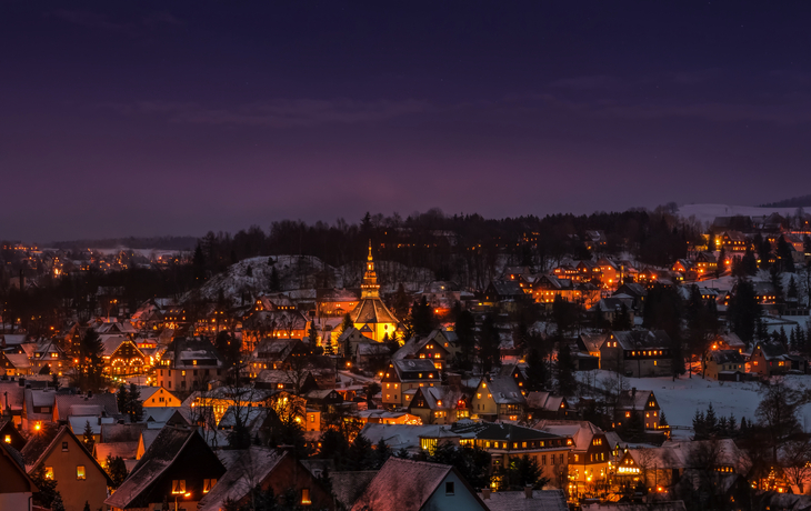 Beleuchtetes Seiffen im Erzgebirge bei Nacht im Winter mit Schnee.