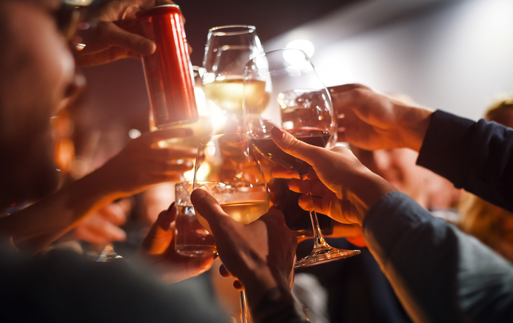 Freunde stoßen mit Gläsern und Getränkedosen bei einer festlichen Feier an.