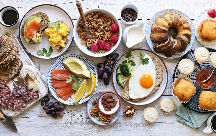 Verschiedene Frühstücksspeisen bei einem Brunch-Buffet mit Brötchen und Getränken.