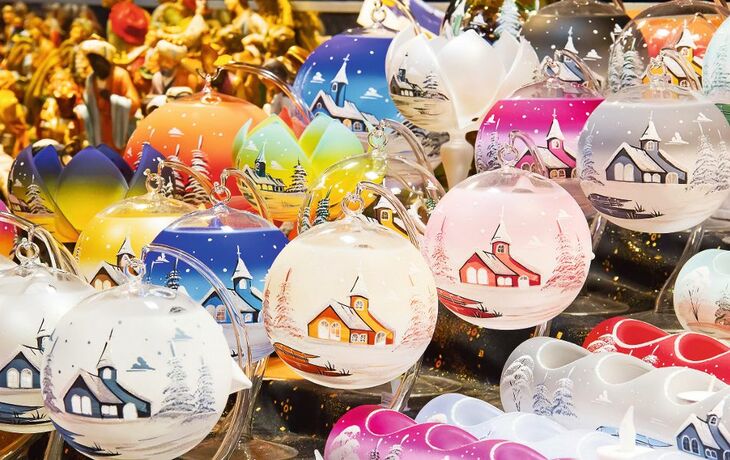 Bunte Weihnachtskugeln mit Landschaftsmotiven auf einem Markt.