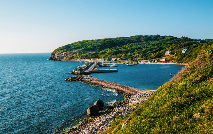 Yachthafen Hammerhavn auf Bornholm mit grüner Küstenlandschaft und blauem Meer.