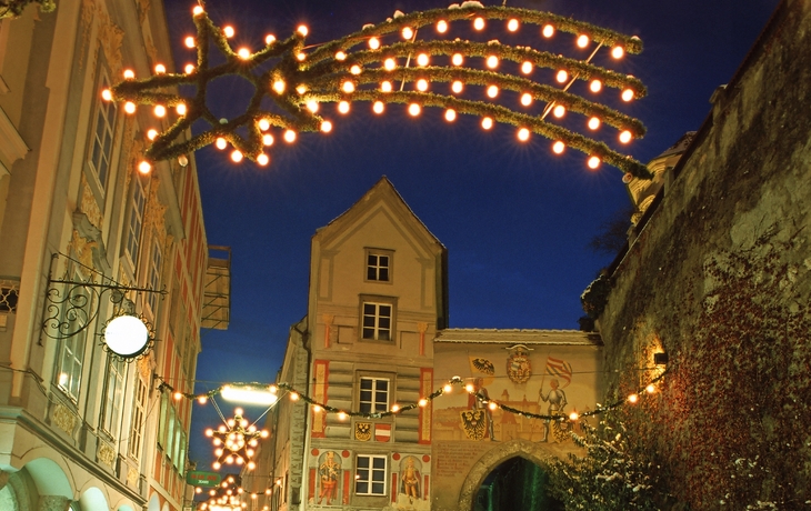 Weihnachtliche Straßenbeleuchtung in einer Altstadt bei Abenddämmerung