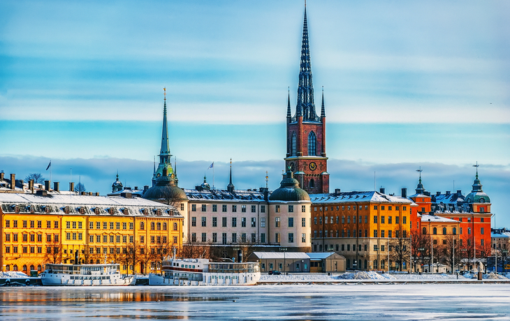 Panorama der Altstadt von Stockholm Gamla Stan im Winter, mit Schnee und Eis bedeckt, im Hintergrund historische Gebäude und Kirchtürme.