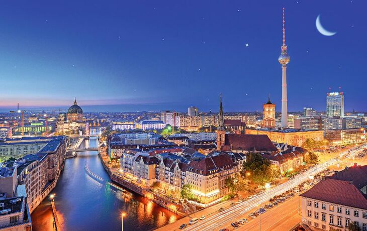 Stadtansicht von Berlin bei Nacht mit Fernsehturm und Spree im Vordergrund.