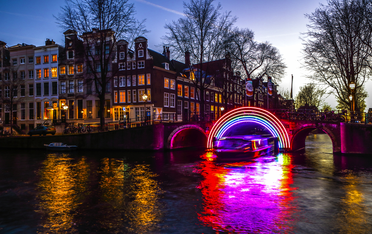Beleuchtete Brücke über einem Kanal bei Dämmerung in einer Stadt.