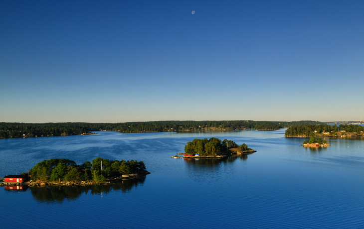 Landschaft mit kleinen Inseln im blauen See unter klarem Himmel.