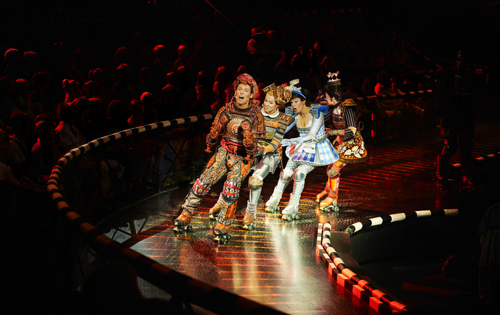 Darsteller des Musicals Starlight Express auf Rollschuhen in bunten Kostümen.