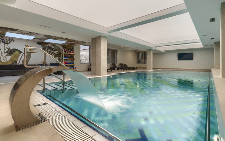 Innenpool mit Liegen und Wasserrutsche in modernem Raum.