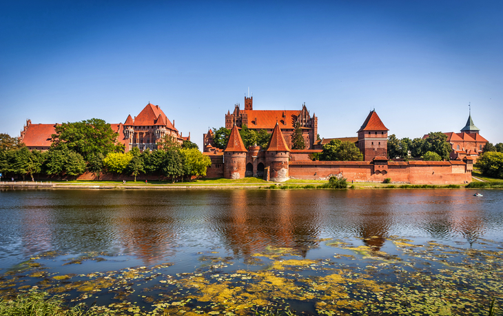 Deutschordensburg Malbork mit dem Fluss Nogat im Vordergrund.