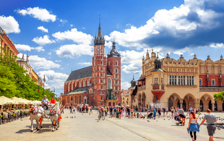 Marienkirche in Krakau mit Menschen und Pferdekutsche auf einem sonnigen Platz.
