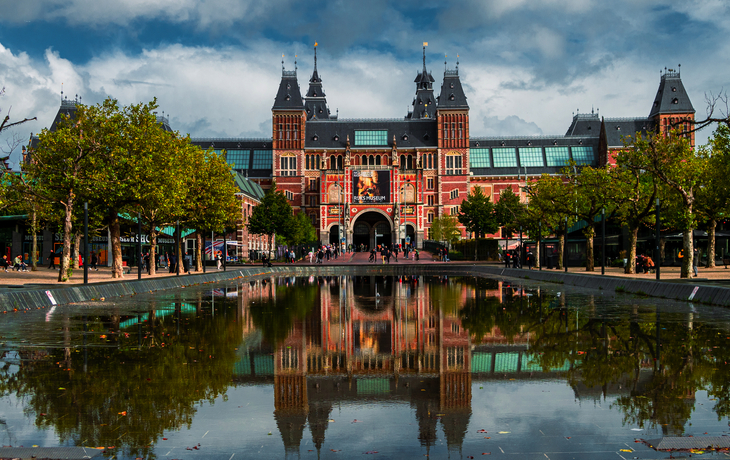 Historisches Gebäude mit reflektierendem Wasser und bewölktem Himmel.