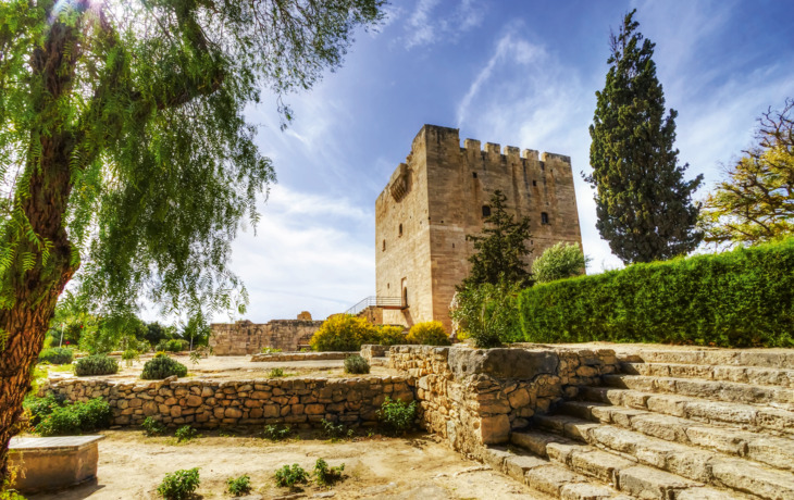 Steinburg mit Garten und Treppe bei sonnigem Himmel.