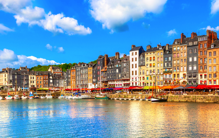 Bunte Häuserreihe am Hafen mit Booten im Wasser und blauem Himmel