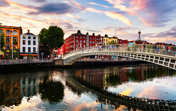 Brücke über einen Fluss mit bunter Architektur bei Sonnenuntergang
