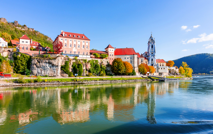 Stift Dürnstein mit blauem Turm und Donau bei Sonnenschein in der Wachau, Österreich.