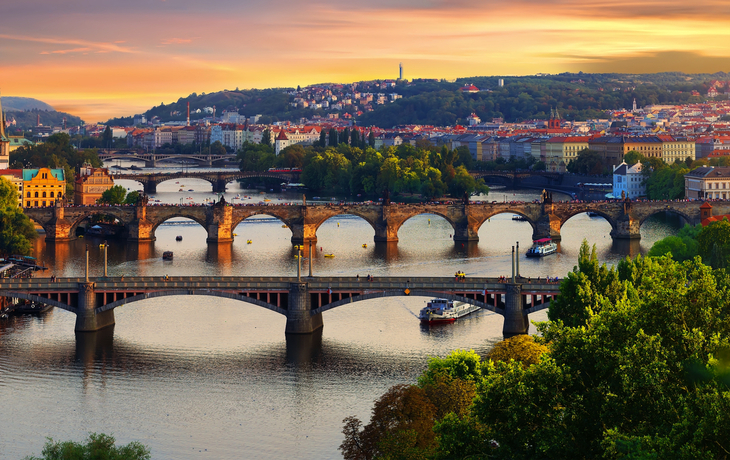 Panorama der Prager Skyline mit Moldau und Karlsbrücke bei Sonnenuntergang.