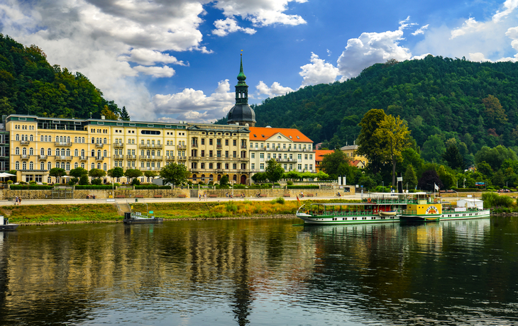 Kurort Bad Schandau an der Elbe mit Fähre und historischen Gebäuden im Hintergrund.