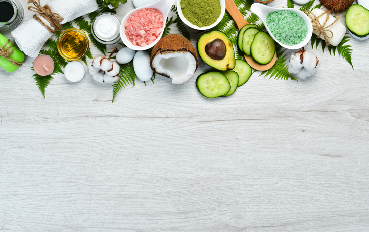 Avocado, Kokosnuss, Gurken und Naturkosmetik auf Holzuntergrund.