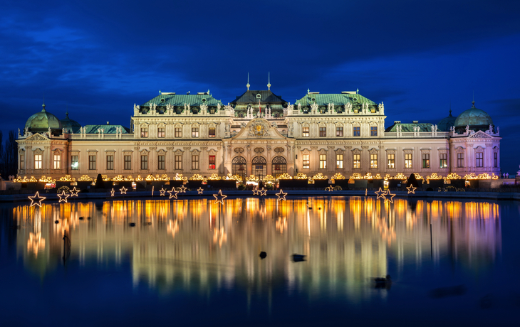 Das Obere Belvedere bei Nacht mit Lichterdekoration und Spiegelung im Wasser.