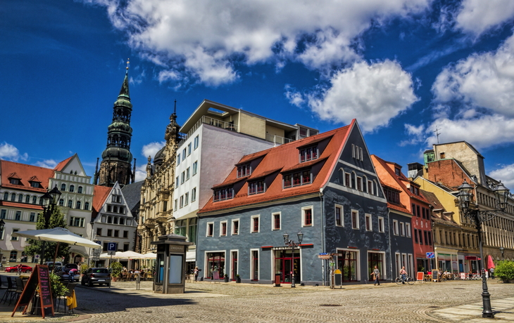 Historische Gebäude an einem sonnigen Platz mit blauem Himmel.