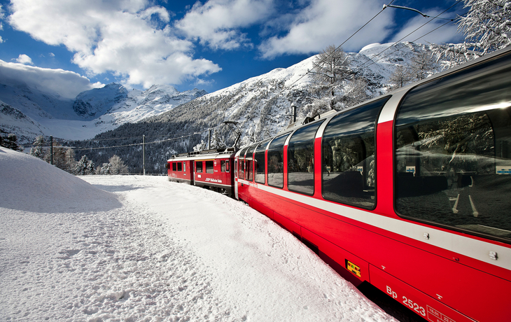 Der Bernina Express windet sich durch eine verschneite Alpenlandschaft.