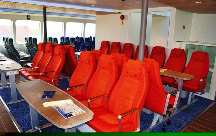 Sitzbereich in einem modernen Passagierschiff mit roten Sitzen und blauen Boden.