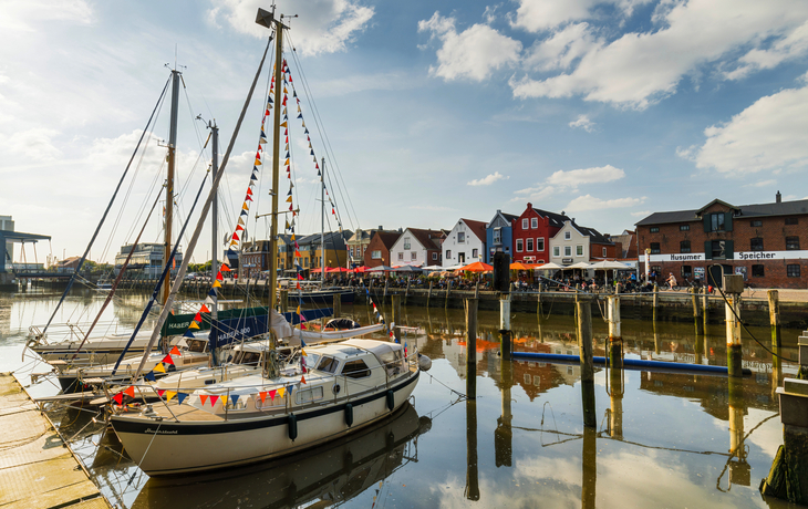 Segelboote im Hafen von Husum, umgeben von traditioneller Architektur und mit Blick auf die Nordsee.