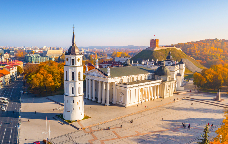 Vilnius-Kathedrale und Glockenturm im Herbst bei klarem Himmel und bunten Bäumen im Hintergrund.