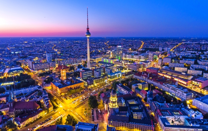 Berliner Skyline bei Nacht mit Fernsehturm und beleuchteten Gebäuden.