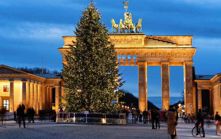 Brandenburger Tor mit Weihnachtsbaum bei Nacht.