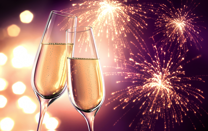 Champagnergläser vor buntem Feuerwerk am Nachthimmel zu Silvester.