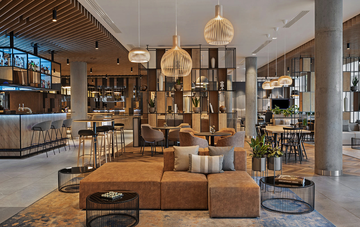 Moderne Hotellobby mit Sitzbereich, Bar und stilvoller Beleuchtung.