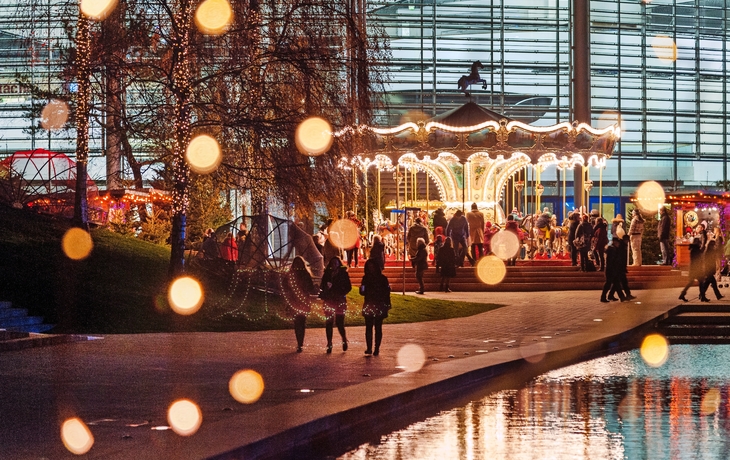 Weihnachtsmarkt in der Autostadt Wolfsburg mit Karussell und Lichtern im Winterabend.