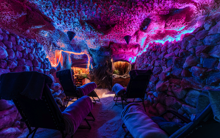 Beleuchtete Entspannungslounge in einer Steinhöhle mit Liegestühlen.