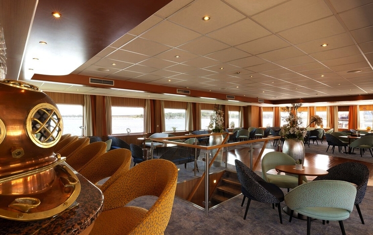 Geräumige Lounge mit Sesseln und Tischen, dekoriert mit antikem Taucherhelm.