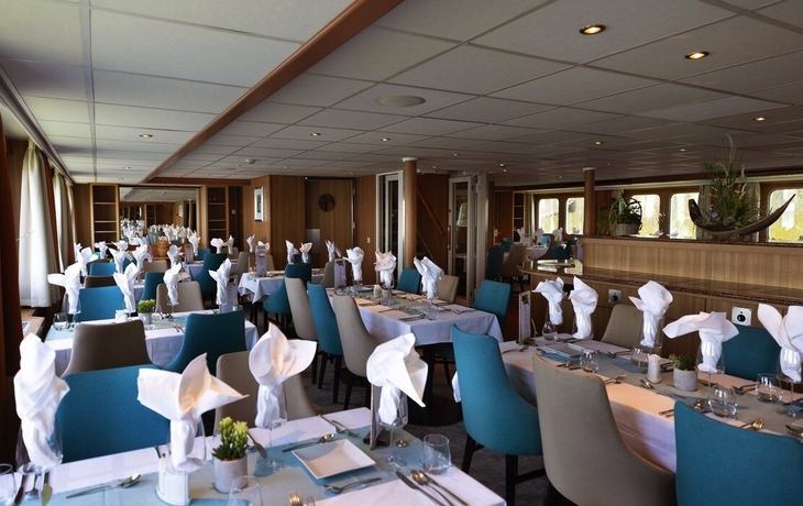 Elegantes Restaurant mit gedeckten Tischen und gefalteten Servietten.