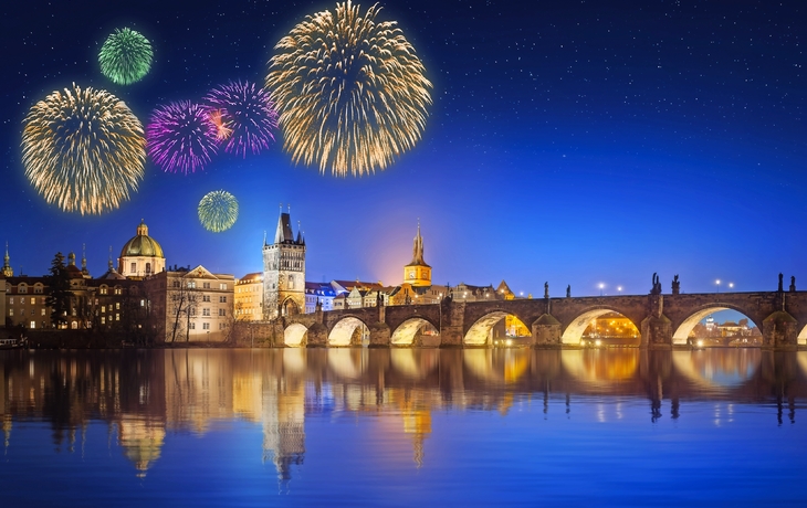 Feuerwerk über nächtlicher Stadtlandschaft mit Brücke und Wasser reflektiert