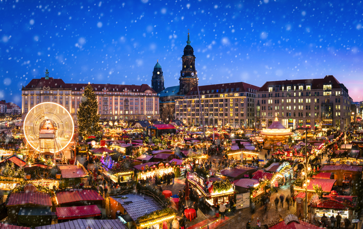 Striezelmarkt in Dresden bei Nacht mit Lichtern und Schnee, Weihnachtsbaum und Karussell.