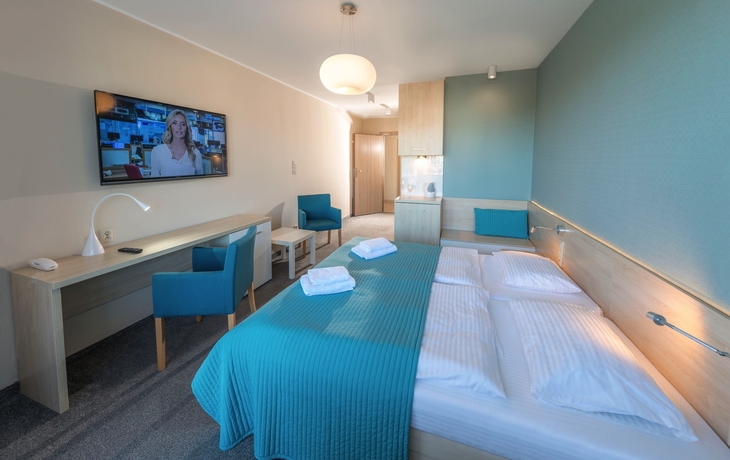 Modern eingerichtetes Hotelzimmer mit Doppelbett und Schreibtisch.