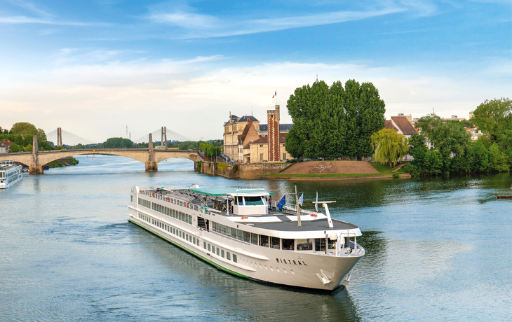 Kreuzfahrtschiff MS Mistral fährt auf einem Fluss unter blauem Himmel.