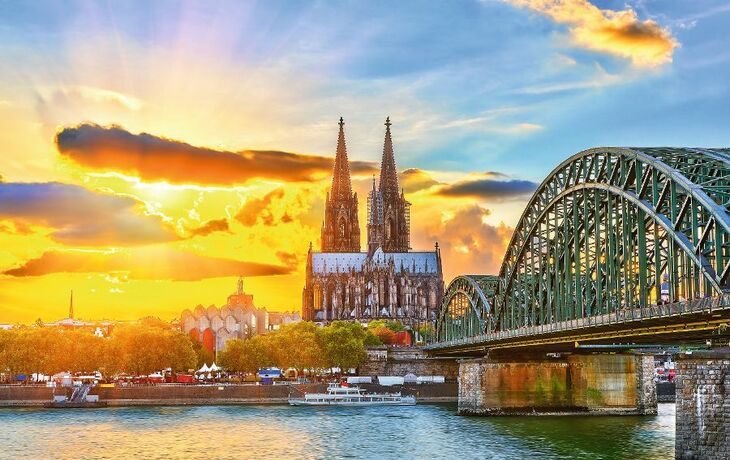 Kölner Dom und Hohenzollernbrücke bei Sonnenuntergang am Rhein.