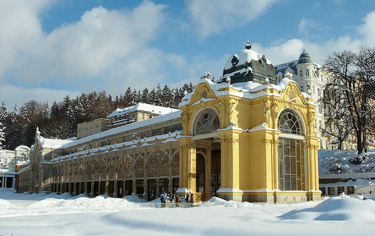 Gelbes Gebäude in Mariánské Lázně im Winter, umgeben von Schnee.