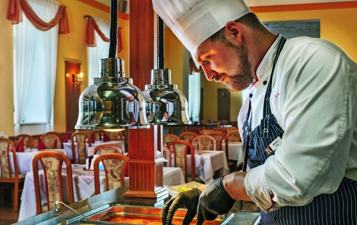 Ein Koch in einem Restaurant bereitet Speisen an einem Buffet zu.
