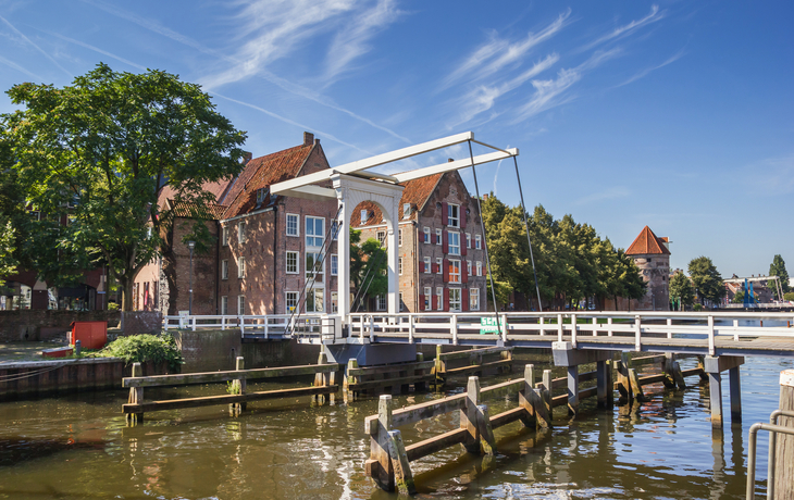 Klappbrücke über einen Kanal mit historischen Backsteingebäuden im Hintergrund.