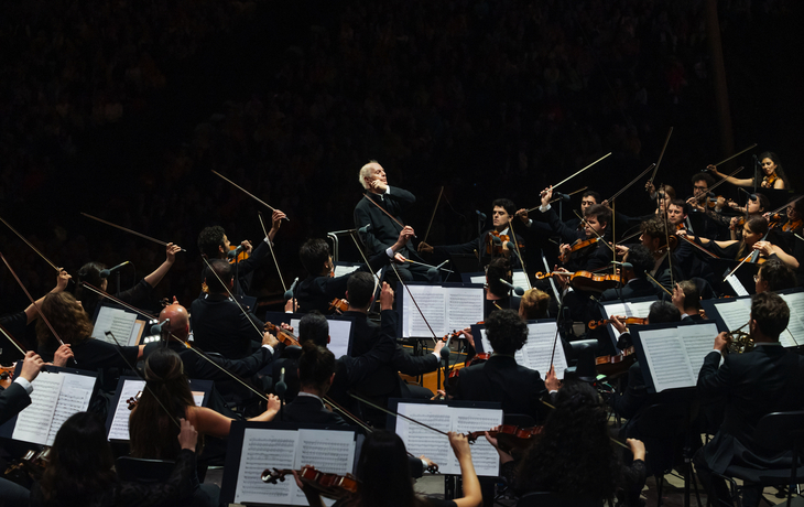 Dirigent führt ein Orchester auf einer Freilichtbühne.