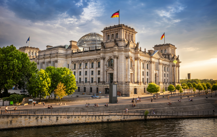 Reichstagsgebäude in Berlin bei Sonnenuntergang, Spiegelung im Wasser der Spree.